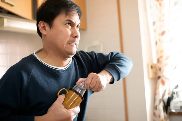 Man pulls out a stuck feeding bottle in a cup or mug. 