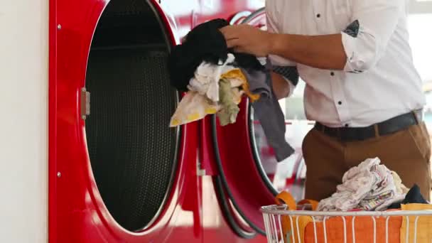 乾燥服 洗濯機で乾燥機に服を入れている男性 — ストック動画