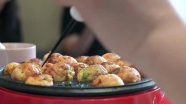 Küçük bir takoyaki makinesinde ev yapımı takoyaki yapmak.