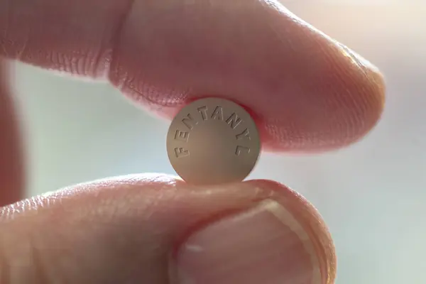 Fentanil ilaç tableti tutan parmaklar. Yakın plan. 