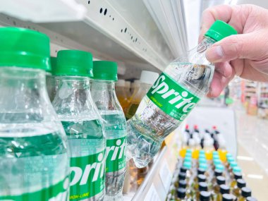 El, süpermarketin rafından bir şişe Sprite alır. 