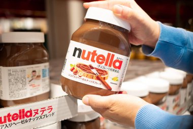 Alışveriş yapan biri market rafından bir şişe Nutella kapar.