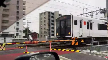 Beyaz JR Kyushu treni Batı Japonya 'da bir demiryolu geçidinde.