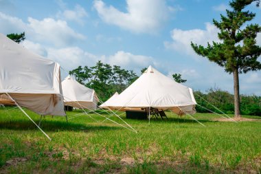 Açık hava yaşam tarzının özünü yansıtan canlı bir mavi gökyüzünün altına kurulmuş doğa çadırlarıyla manzaralı bir kamp alanı..