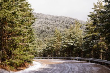 Madrid 'deki Sierra de Guadarrama dağlarında hafif karlı bir yol 2022 yılının ilk karı ile