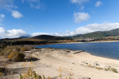 Sonbaharda Navacerrada rezervuarı, arka planda kasaba ve Madrid 'deki Sierra de Guadarrama dağları ile birlikte.