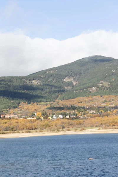 Stock image Navacerrada reservoir in autumn with the town in the background and the mountains of the Sierra de Guadarrama in Madrid