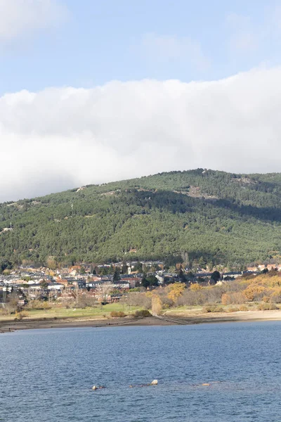 stock image Navacerrada reservoir in autumn with the town in the background and the mountains of the Sierra de Guadarrama in Madrid