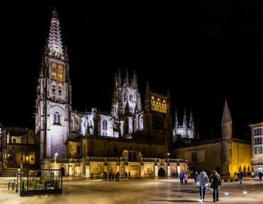 Burgos Cathedral with people and tourists walking past in the square next to the Cathedral of Saint Mary, in Burgos, Spain