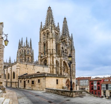 Burgos Cathedral with people and tourists walking past in the square next to the Cathedral of Saint Mary, in Burgos, Spain