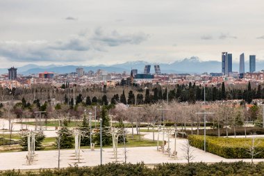 Madrid 'in gökdelenleri, arka planda dört kule ve karlı dağlar ve önde La Almudena mezarlığı.