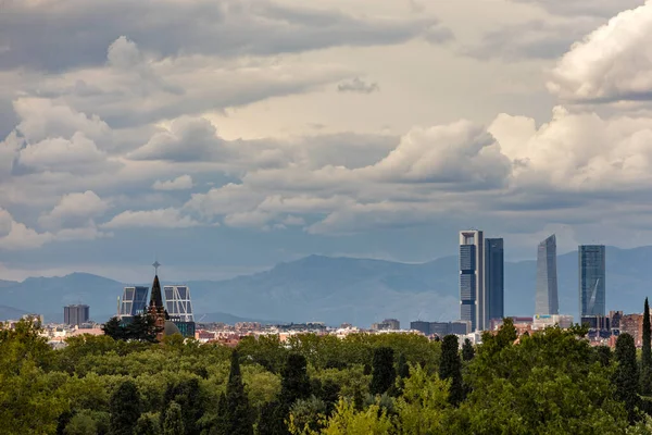 stock image Skyline of Madrid with skyscrapers the four towers and snowy mountains in the background, and in the cemetery of La Almudena in the front