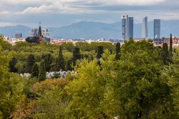 马德里的天际线 后面是摩天大楼 后面是四座塔 后面是雪山 前面是拉阿尔穆迪纳公墓 — 图库照片