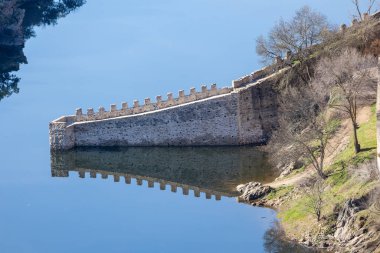 Duvarlarla çevrili Buitrago del Lozoya kasabası ve dağlardan akan nehir manzaralı manzara.