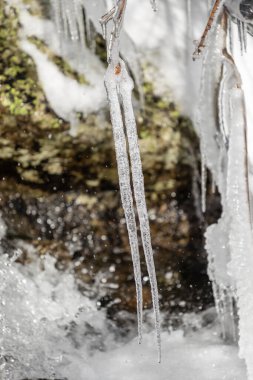 Açık mavi gökyüzüne karşı buz saçağı. Erimiş kar damlası düşer. Yakın çekim..