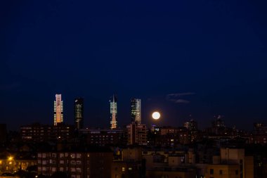 The moon over the four towers in the city of Madrid, Spain