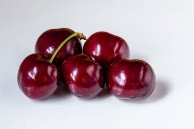 Olgun kiraz yığınını yaprak ve saplarla kapatın. Büyük bir taze kırmızı kiraz koleksiyonu. Olgun kiraz arkaplanı.