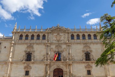 Alcala de Henares - 5 Mayıs 2025: Üniversitenin ana cephesi, İspanya 'nın Alcala de Henares kentinin tarihi merkezine girmek için bekleyen ziyaretçilerle birlikte