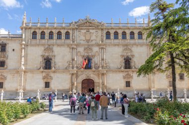 Alcala de Henares - 5 Mayıs 2025: Üniversitenin ana cephesi, İspanya 'nın Alcala de Henares kentinin tarihi merkezine girmek için bekleyen ziyaretçilerle birlikte