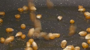 Adding corn kernels to pan, preparing homemade popcorn 4k detail