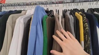 Kumaşa dokunmak ve ikinci el mağazasındaki giysi raflarını aramak, adam ve unisex koleksiyonu 4K görüntü