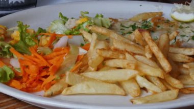 Bir restoranda patates cipsi, kümes hayvanı ve sebze salatası yemek.