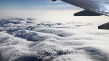 Uçak penceresinden çarpıcı bulutların gerçek 4K görüntüsü, peri masalı gibi görünüyor.