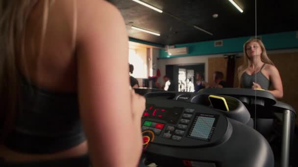 健身女人在健身房的跑步机上跑步 运动员在健身中心使用跑步机 漂亮的女孩在体育俱乐部做有氧运动训练 120Fps — 图库视频影像