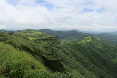 Güzel, yemyeşil Sahyadri Dağları 'ndaki Sinhgad Kalesi' nin güçlü çevre duvarının panoramik manzarası. Sinhgad kalesi Pune, Maharashtra, Hindistan 'da ünlü bir turistik yerdir.