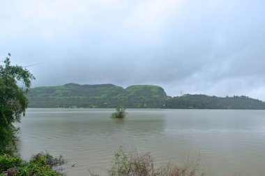 Bulutlu bir muson gününde güzel Mulshi Gölü manzarası. Bereketli yeşil dağlar ve yoğun sis ile çevrili olan bölge, Mulshi, Pune, Maharashtra, Hindistan 'da ünlü bir turistik noktadır.