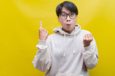 Reklam ve ürün yerleştirme kavramları için mutlu, gülümseyen Asyalı genç bir adam avuçlarını açar ve uzayı kopyalamak için işaret eder.