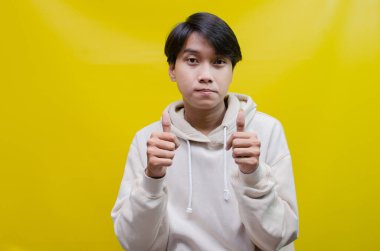 Reklam ve ürün yerleştirme kavramları için mutlu, gülümseyen Asyalı genç bir adam avuçlarını açar ve uzayı kopyalamak için işaret eder.