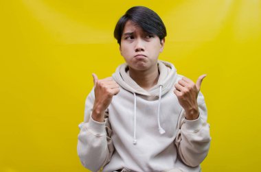 Reklam ve ürün yerleştirme kavramları için mutlu, gülümseyen Asyalı genç bir adam avuçlarını açar ve uzayı kopyalamak için işaret eder.