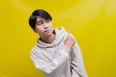 Reklam ve ürün yerleştirme kavramları için mutlu, gülümseyen Asyalı genç bir adam avuçlarını açar ve uzayı kopyalamak için işaret eder.