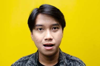 Havalara uçmuş, bej kapüşonlu, yakışıklı Asyalı genç bir adam.