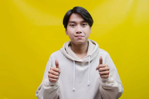 Reklam ve ürün yerleştirme kavramları için mutlu, gülümseyen Asyalı genç bir adam avuçlarını açar ve uzayı kopyalamak için işaret eder.