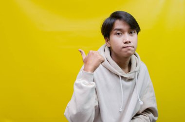 Reklam ve ürün yerleştirme kavramları için mutlu, gülümseyen Asyalı genç bir adam avuçlarını açar ve uzayı kopyalamak için işaret eder.