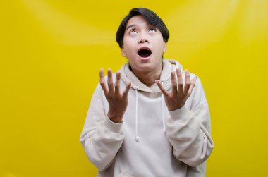 Reklam ve ürün yerleştirme kavramları için mutlu, gülümseyen Asyalı genç bir adam avuçlarını açar ve uzayı kopyalamak için işaret eder.