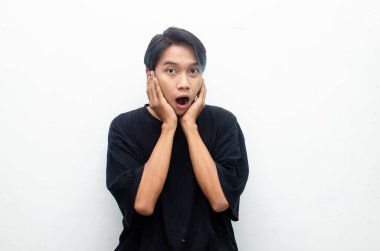 Siyah tişörtlü genç Asyalı adam beyaz bir arkaplan görünce şok oldu.. 