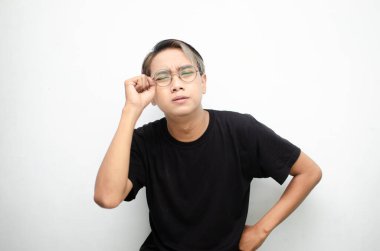 Siyah tişört giyen genç Asyalı adamın portresi. Çaresiz görünüyor ve beyaz arka planda yalnız başına ağlıyor.   