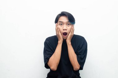Stüdyo arka planında şok olmuş genç bir Asyalı. 