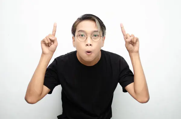 stock image young Asian man pointing up at studio background 