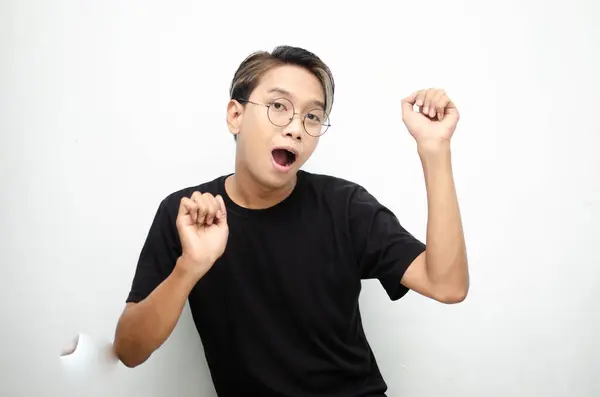 Siyah tişört giyen Asyalı genç bir adamın portresi zaferi kutluyor beyaz arka planda izole edilmiş.   