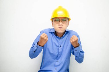 Asyalı kızgın inşaat işçisi sarı kaskı takıyor. 