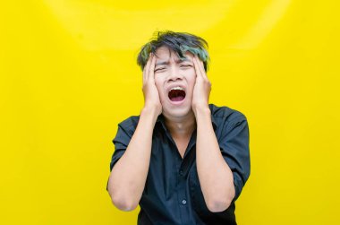 Asyalı genç adam sarı arka planda stresli 