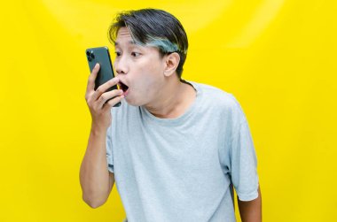 Akıllı telefonlu kızgın ve şok olmuş bir Asyalı. 