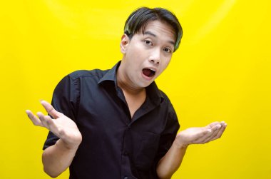 Sarı arka planda ağzı açık poz veren hayal kırıklığına uğramış Asyalı genç bir adamın portresi..