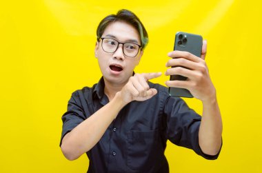 Sarı arka planda telefon kullanan genç Asyalı adam. 