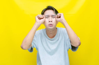 Stresli, depresif Asyalı genç adam sarı arka plan 