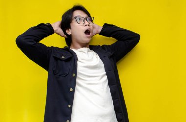 Sarı arka planda genç Asyalı bir adam var. 